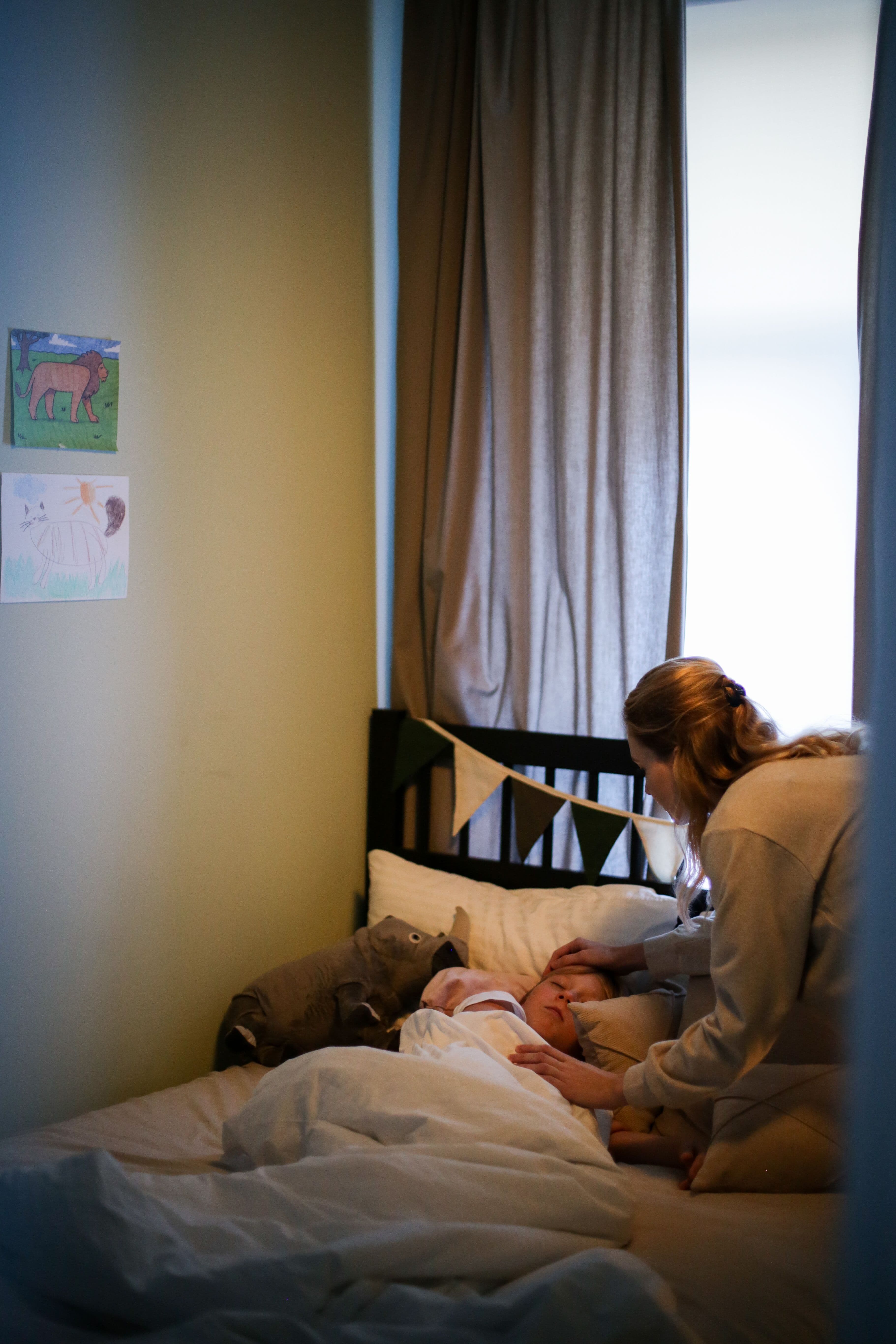 A parent tucking their child in at bedtime, lit warmly in a cozy bedroom